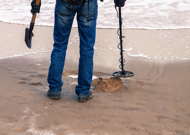 Mężczyzna używający wykrywacza metalu do poszukiwania metalu lub zagubionego skarbu na piaszczystej plaży