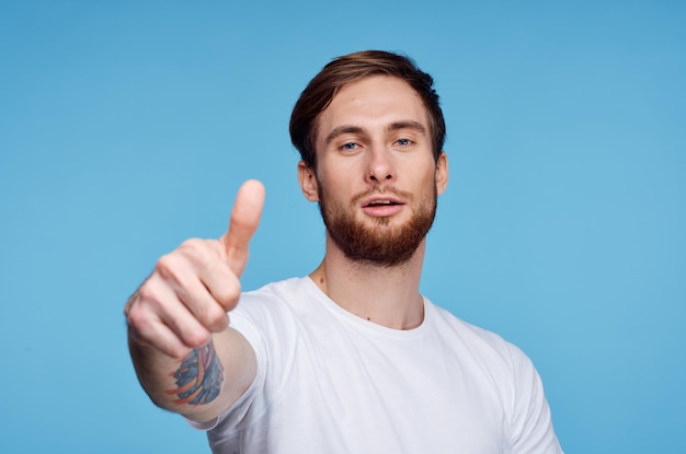 Mężczyzna w białej koszulce pokazując kciuk do góry niebieskie tło studio