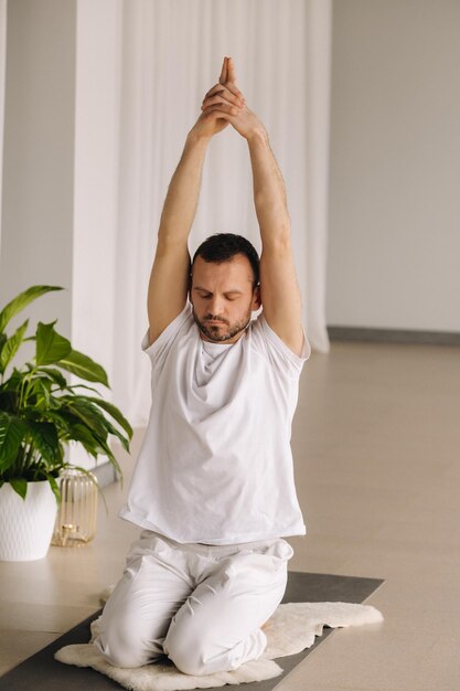 Mężczyzna w białej odzieży sportowej robi jogę z salą fitness koncepcja zdrowego stylu życia