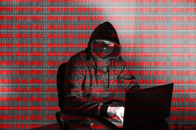 Mężczyzna w bluzie z kapturem włamuje się do danych osobowych. Bezpieczeństwo informacji. Koncepcja wirtualnego wirusa. Ochrona informacji. Złe hasło.
