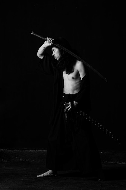 Mężczyzna w czarnej szacie trzyma nad głową miecz.