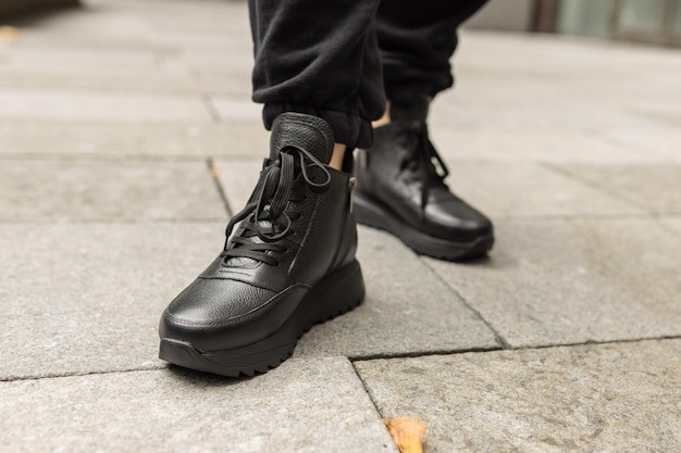 Mężczyzna w czarnych butach stoi na chodniku.