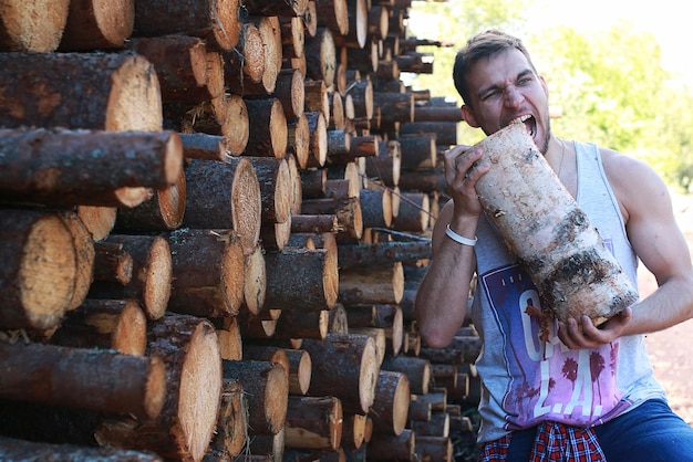 Mężczyzna w fabryce przetwarzający drewno, piłujący kłody i drewno opałowe