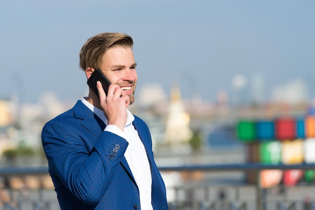 Mężczyzna w formalnym stroju z telefonem komórkowym Menedżer z brodą na zadowolonej twarzy trzymaj telefon nowoczesne życie i nową technologię Komunikacja biznesowa i marketing cyfrowy Biznesmen lub dyrektor generalny moda miejska