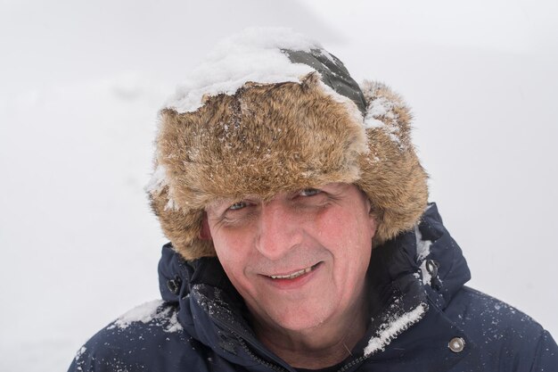 Mężczyzna w futrzanej czapce zimowej na białym tle portretu śniegu