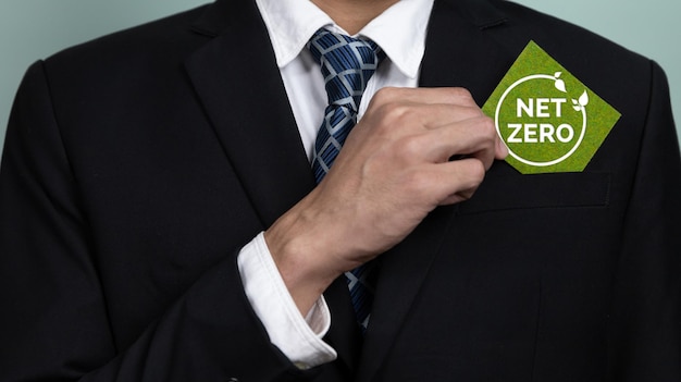 Mężczyzna w garniturze stawia zielony znak z napisem Nowa Zelandia.