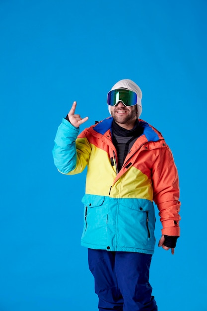 Zdjęcie mężczyzna w goglach snowboardowych uśmiecha się i robi rogi