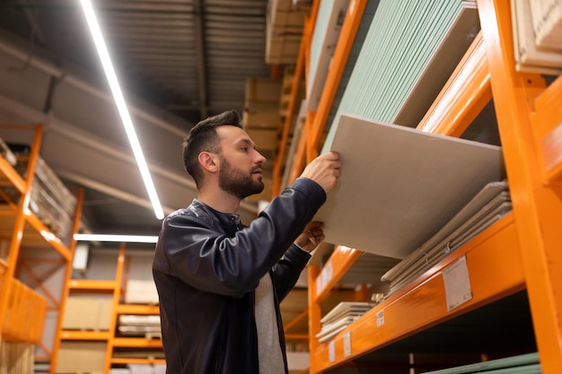 Mężczyzna w hipermarkecie budowlanym wybiera materiały do dekoracji ścian ogląda płyty osb i