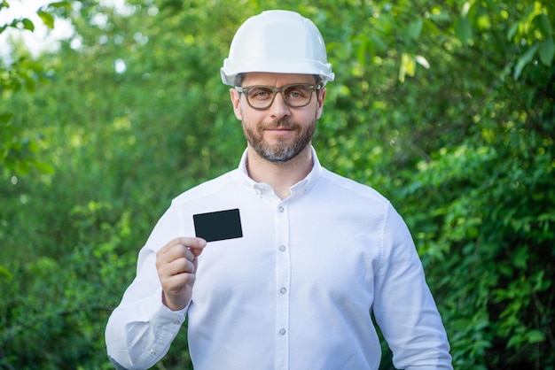 Mężczyzna w kasku pokazujący pustą kartę kontaktową na zewnątrz miejsca kopiowania
