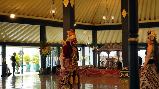 Mężczyzna w kostiumie stoi przed świątynią z dużą wystawą balijskich dekoracji.