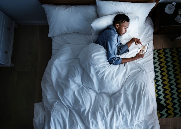 Mężczyzna w łóżku za pomocą cyfrowego urządzenia w ciemności