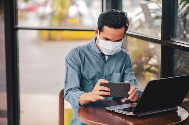 Mężczyzna w masce medycznej za pomocą laptopa