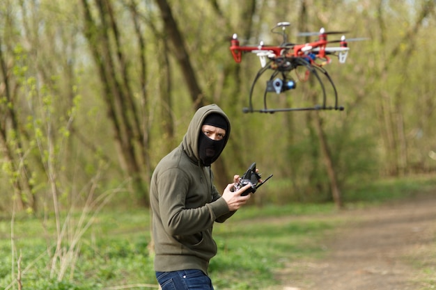 Mężczyzna w masce obsługujący drona z pilotem