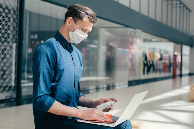 Mężczyzna W Masce Ochronnej Dezynfekuje Laptopa. Pandemia W Mieście