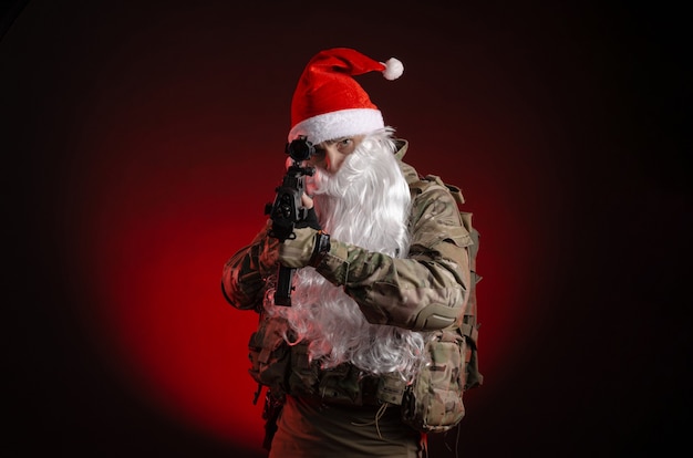 Mężczyzna w mundurze wojskowym z pistoletem i czapką Świętego Mikołaja