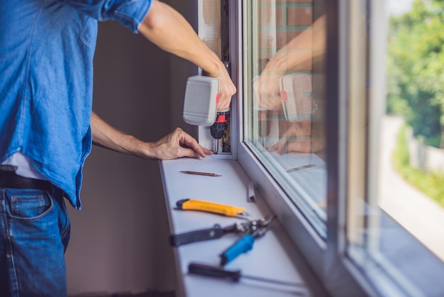 Mężczyzna w niebieskiej koszuli wykonuje instalację okienną.