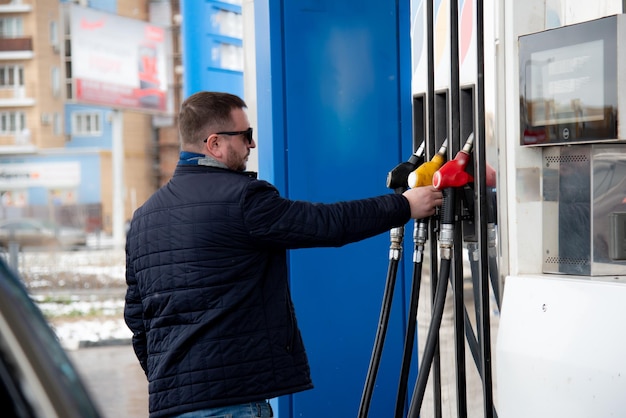 Zdjęcie mężczyzna w niebieskiej marynarce i ciemnych okularach na stacji benzynowej tankuje samochód petrol lifestile