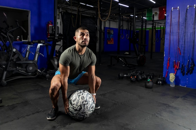 Mężczyzna w odzieży sportowej ćwiczący z piłką lekarską crossfit na siłowni