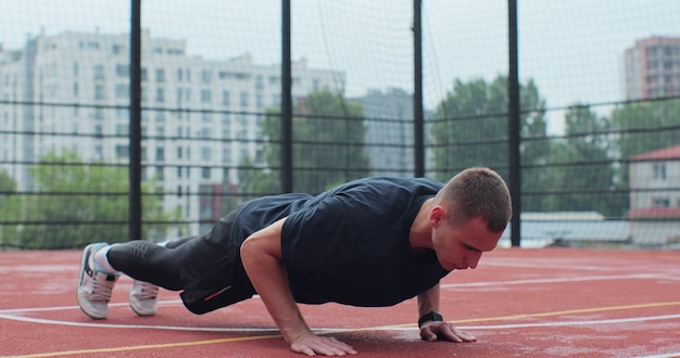 Mężczyzna w odzieży sportowej robi ćwiczenia pushup na boisku do koszykówki Koncepcja zdrowego stylu życia i sportu