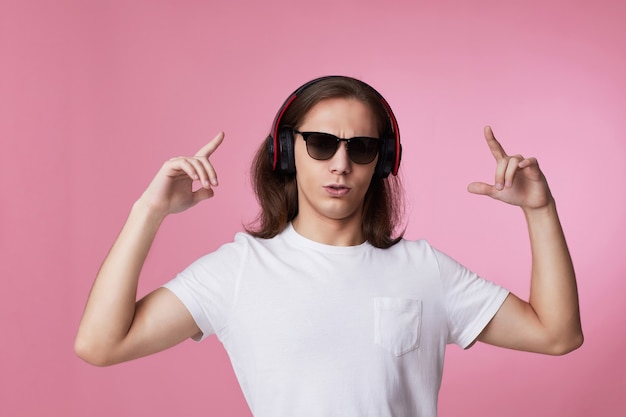 Mężczyzna w okularach przeciwsłonecznych słucha muzyki przez słuchawki i tańczy