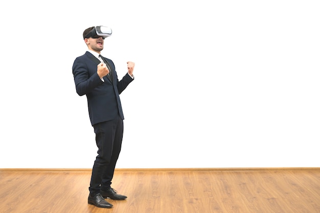 Mężczyzna w okularach wirtualnej rzeczywistości gestykuluje na tle białej ściany