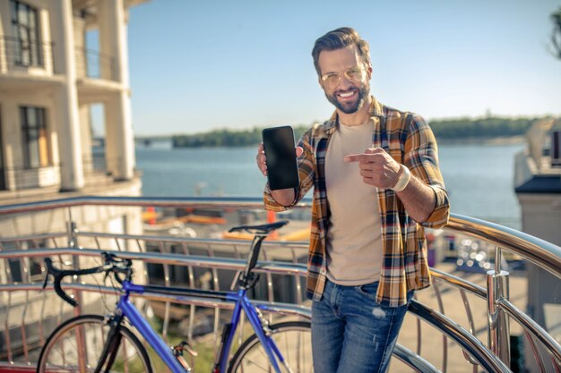 Mężczyzna w pobliżu roweru ze smartfonem w rękach