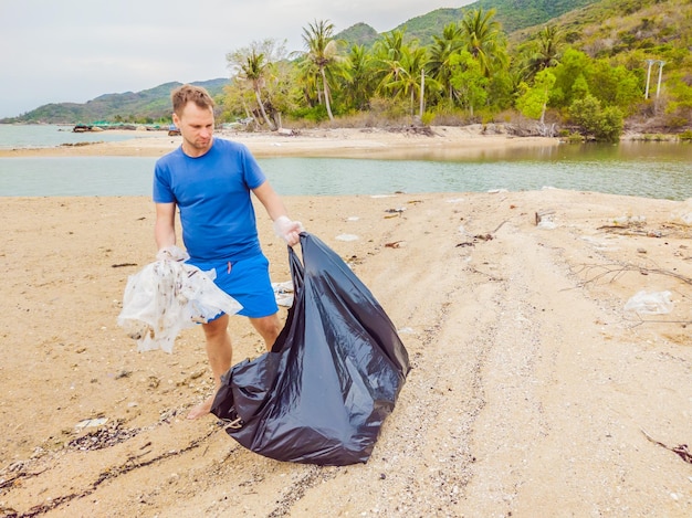 Mężczyzna W Rękawiczkach Podnosi Plastikowe Torby, Które Zanieczyszczają Morze