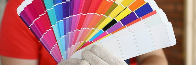 Mężczyzna W Rękawiczkach Pokazuje Próbki Kolorów W Krzywym Zarysie Paletę Kolorów Do Tworzenia