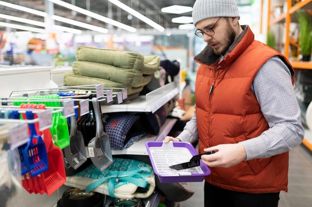 Mężczyzna w sklepie zoologicznym wybiera toaletę dla kota