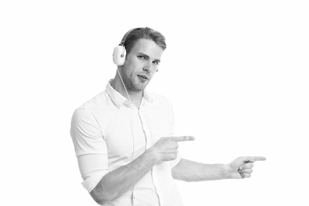 Mężczyzna w słuchawkach wskazujący palec wskazujący na białym tle Centrum obsługi telefonicznej asystenta pomaga znaleźć kierunek Pracownik serwisu telefonicznego wskazuje kierunek Spójrz na ten przewodnik Mężczyzna słucha muzyki w słuchawkach