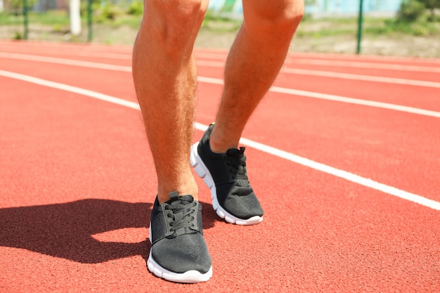 Mężczyzna w sneakers na czerwonym sportowym bieg śladzie, zamyka up