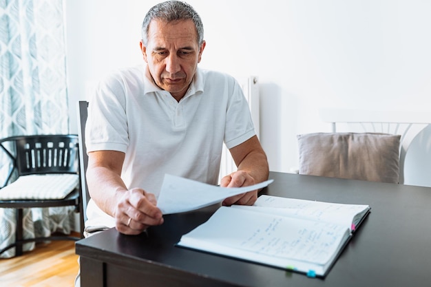 Mężczyzna w średnim wieku czyta rachunek lub list przy stole w domu