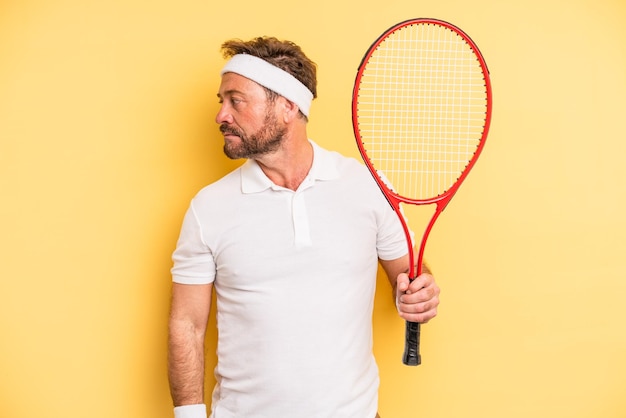 mężczyzna w średnim wieku na widoku profilu myślący, wyobrażający sobie lub marzący. koncepcja tenisa