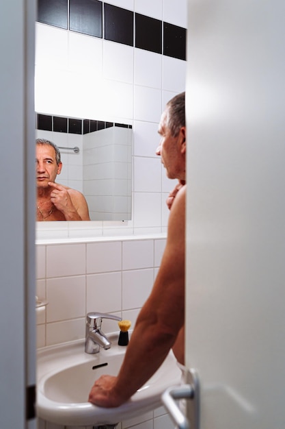 Mężczyzna w średnim wieku patrząc w lustro w łazience