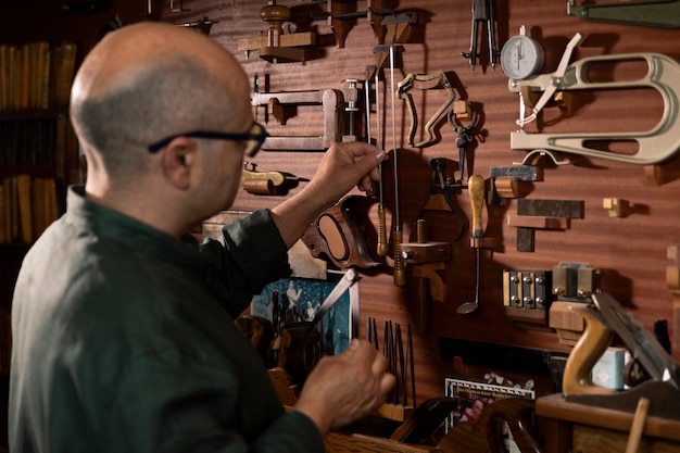 Zdjęcie mężczyzna w średnim wieku sam wytwarza instrumenty w swoim warsztacie