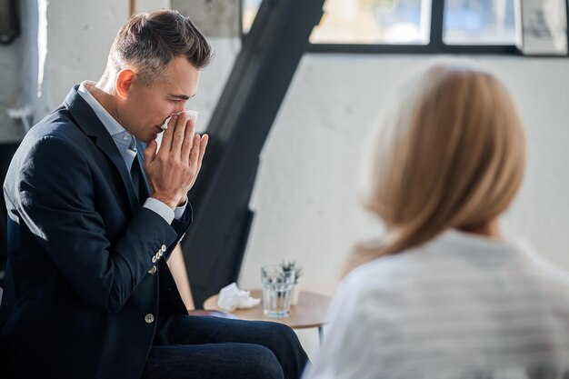 Zdjęcie mężczyzna w średnim wieku wyglądający na zdenerwowanego i opowiadający o swoich problemach psychologowi