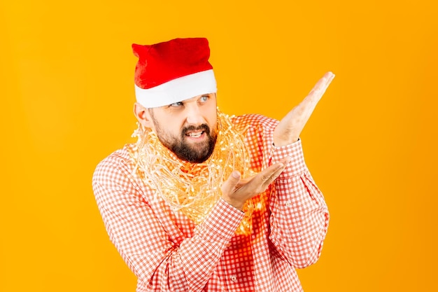 Mężczyzna w stroju noworocznym i ze świąteczną girlandą na szyi pokazuje gesty rękami i uśmiechem