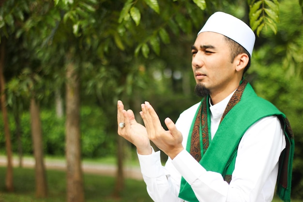 Zdjęcie mężczyzna w tradycyjnych ubraniach modlący się przeciwko drzewom