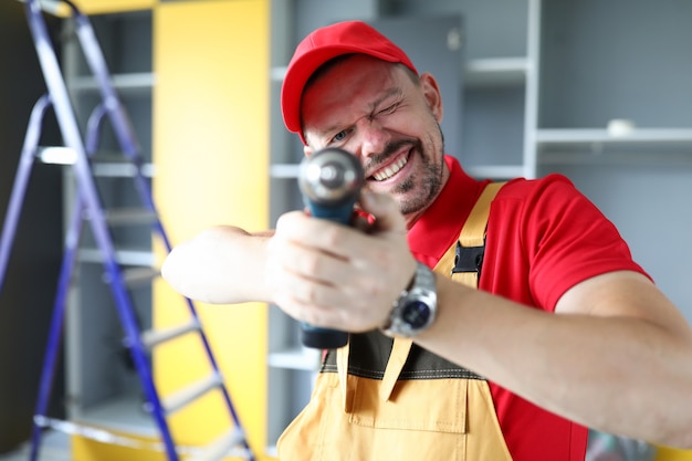 Mężczyzna W Ubraniu Roboczym Celuje W śrubokręt I Uśmiecha Się Stolarz Montuje Meble W Domu