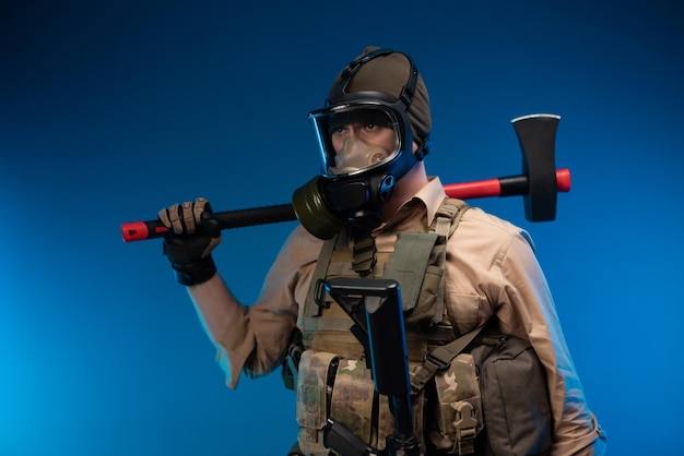mężczyzna w wojskowym ubraniu i masce gazowej z czerwonym toporem strażackim na ramieniu