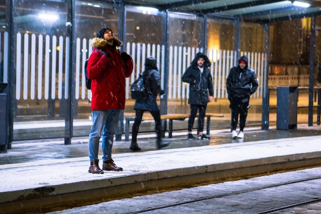 Mężczyzna w zimową noc na dworcu czeka na tramwaj