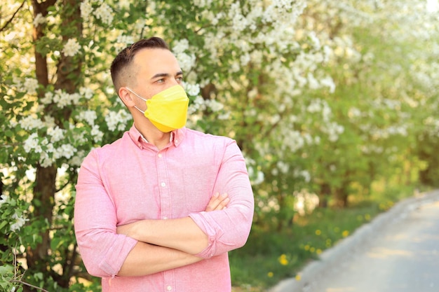 Mężczyzna w żółtej masce medycznej w parku sezonowa ochrona przed alergią Miejsce na tekst