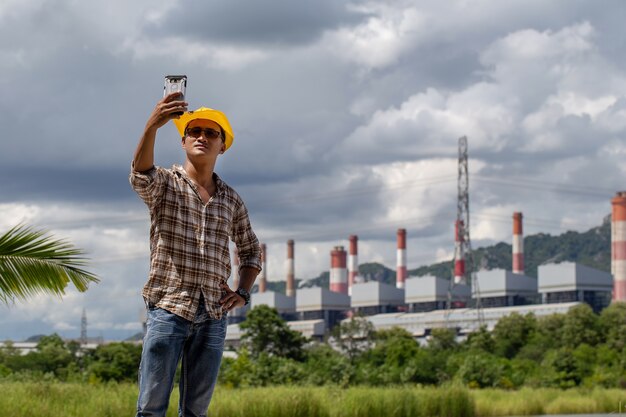 Mężczyzna w żółtym kapeluszu fotografował się z elektrownią w tle