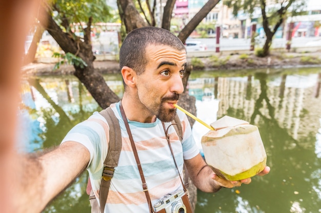 Mężczyzna weź selfie i wypij wodę kokosową w Bangkoku