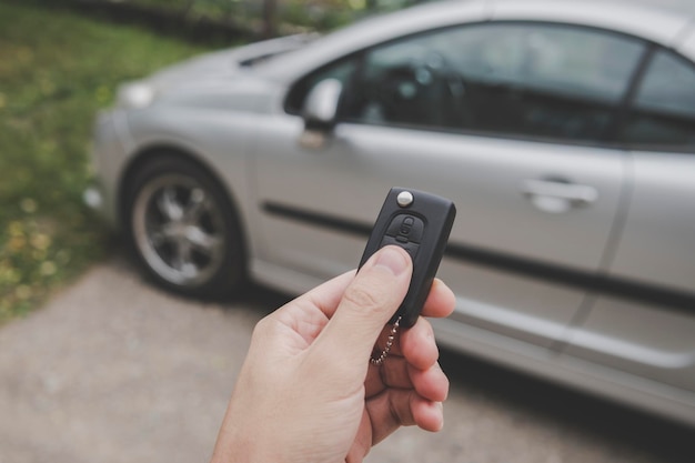 Mężczyzna właściciel samochodu wyłącza system alarmowy i odblokowuje drzwi samochodu za pomocą kluczyków z pilotem zdalnego sterowania na tle parkingu Mężczyzna rozpoczyna podróż samochodem Podróż samochodem Autokontrola