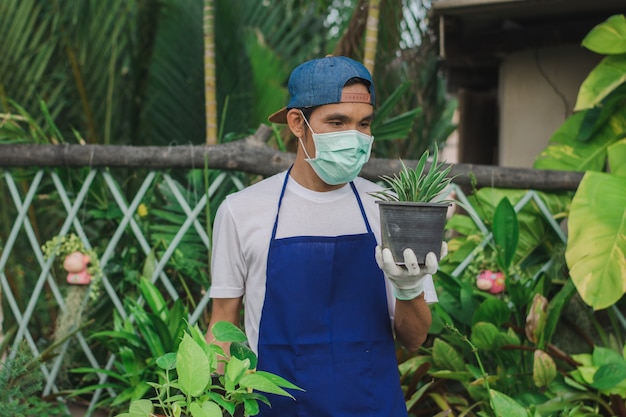 Mężczyzna właściciel sklepu ogrodniczego nosi maskę na twarz pracujący w kwiaciarni