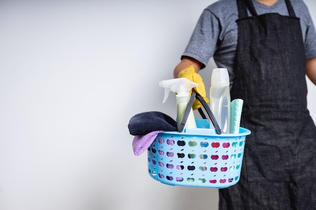 Mężczyzna woźny trzymający kosz ze środkami czyszczącymi przygotowującymi się do sprzątania w domu