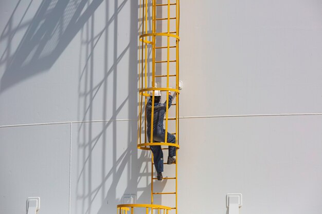 Mężczyzna wspina się po schodach drabina do przechowywania kontroli wizualnej zbiornik gazu propan