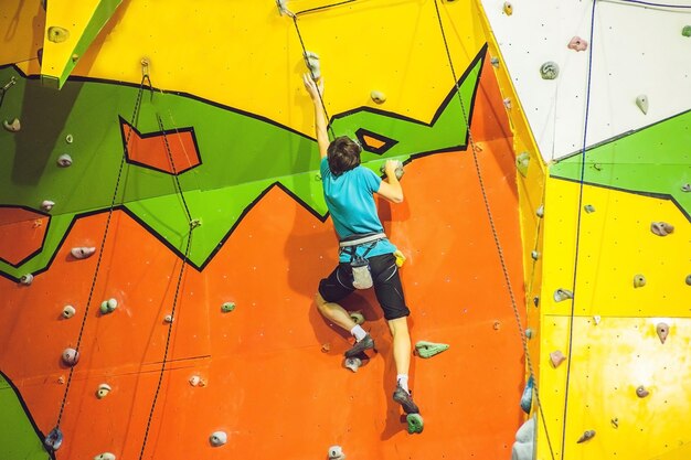 Mężczyzna wspinacz na sztucznej ściance wspinaczkowej w bouldering gym.