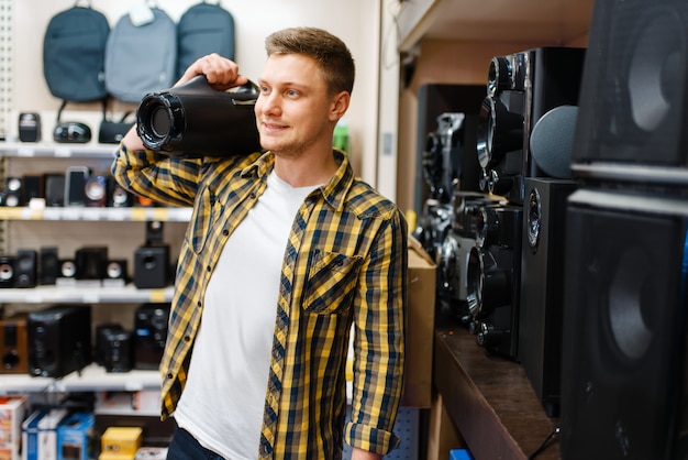 Zdjęcie mężczyzna wybiera system muzyczny w sklepie elektronicznym. mężczyzna kupuje domowe urządzenia elektryczne na rynku